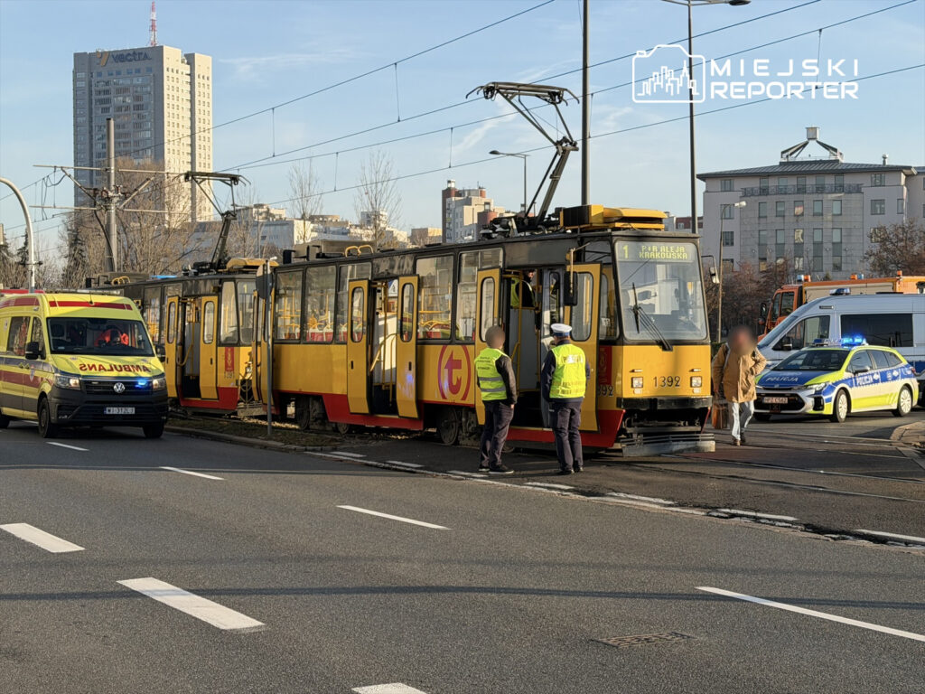 Tramwaj z numerem 1392 zatrzymany na ulicy, obok stoją karetka pogotowia i radiowóz policji, a funkcjonariusze rozmawiają.