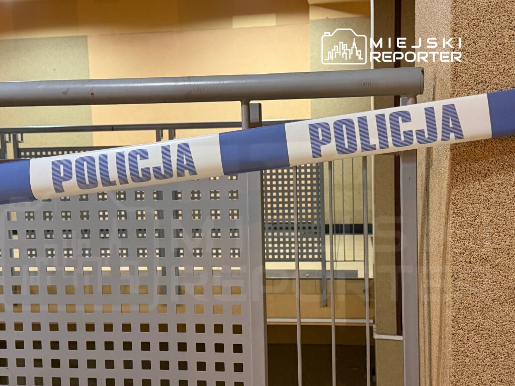 Niebieska taśma policyjna zabezpieczająca przejście w nowoczesnym wnętrzu budynku.