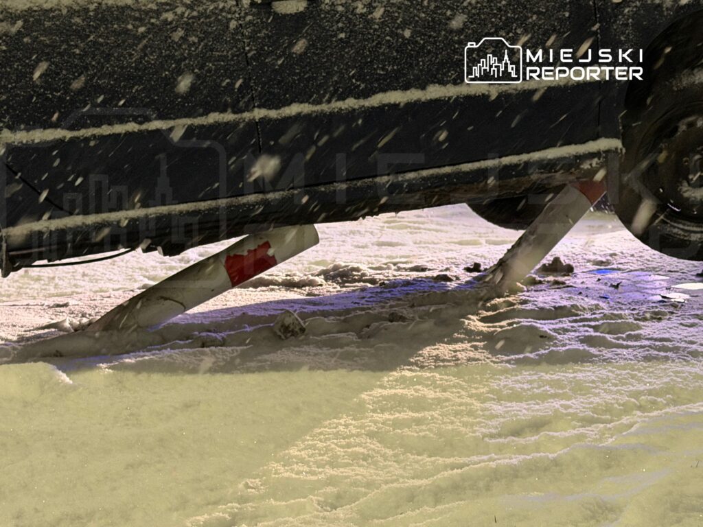 Samochód unosi się na dwóch śnieżnych słupkach w zimowym otoczeniu, z opadającym śniegiem wokół.