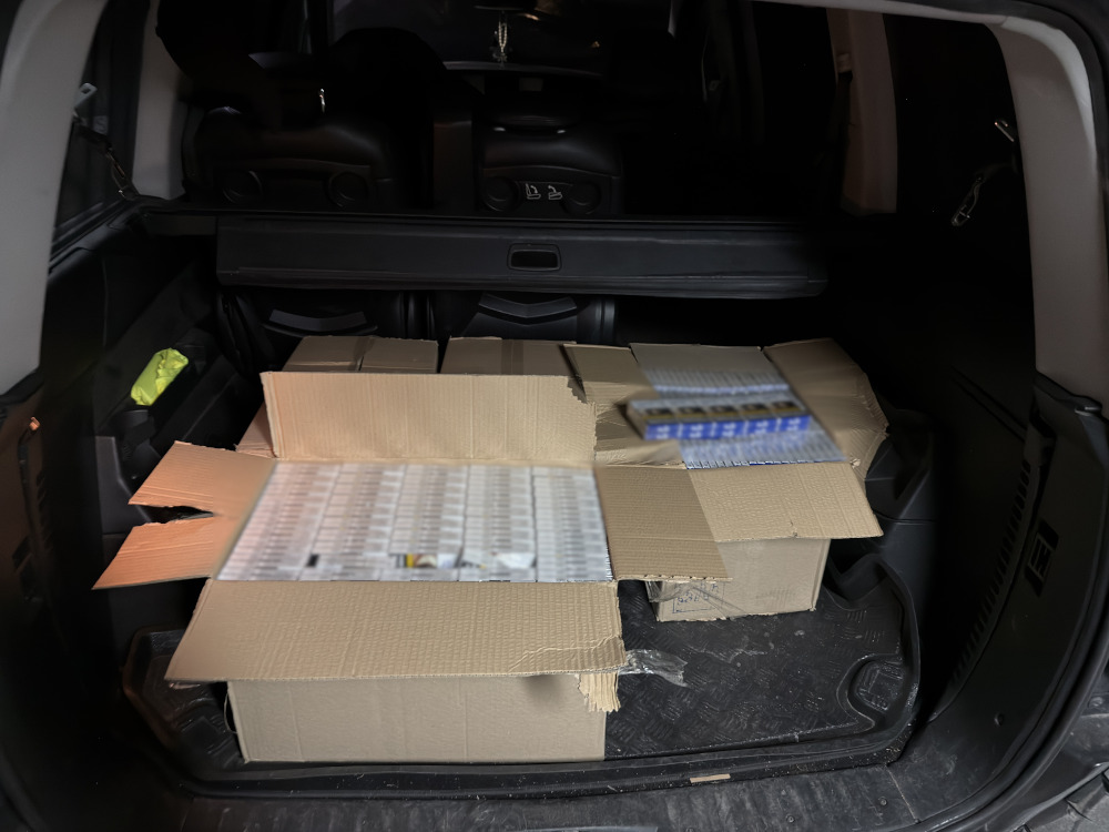 W bagażniku samochodu znajdują się otwarte kartony z zawartością, częściowo widoczne opakowania.