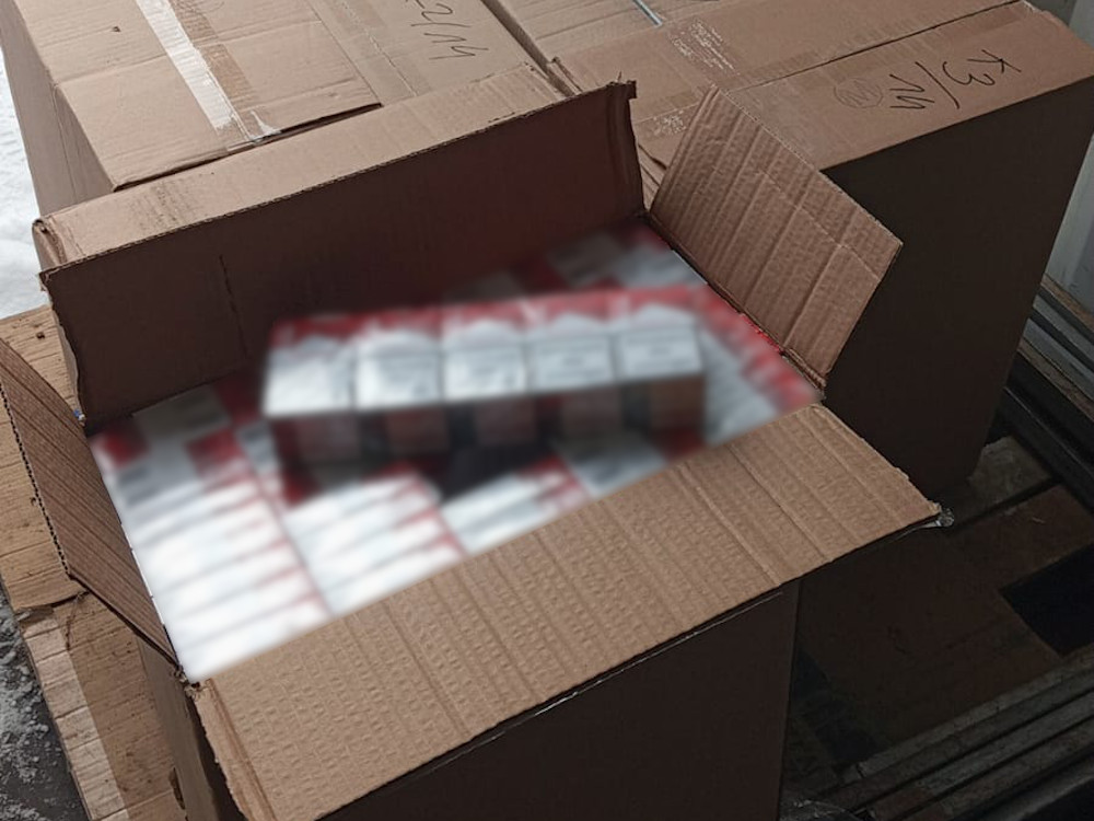 Otwarta kartonowa skrzynka z widocznymi produktami w środku, umieszczona na podłodze w magazynie.