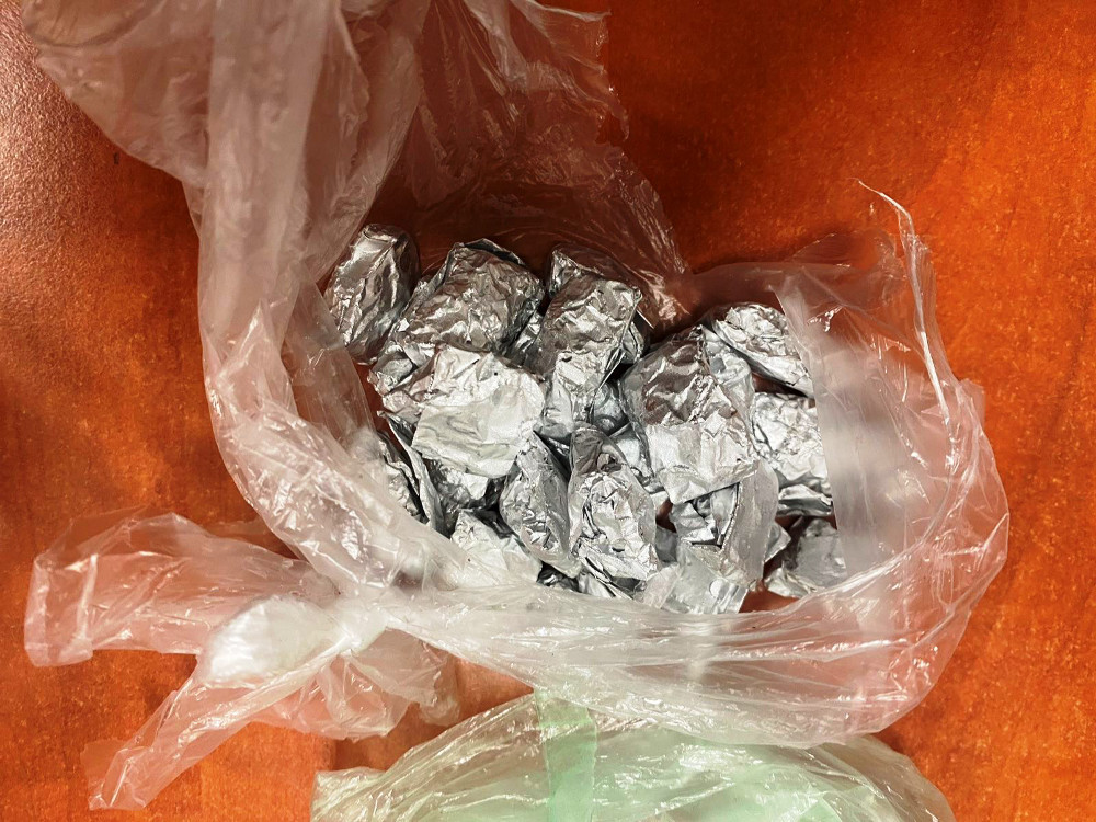 Srebrne pakunki w przezroczystej torbie leżą na drewnianym blacie.