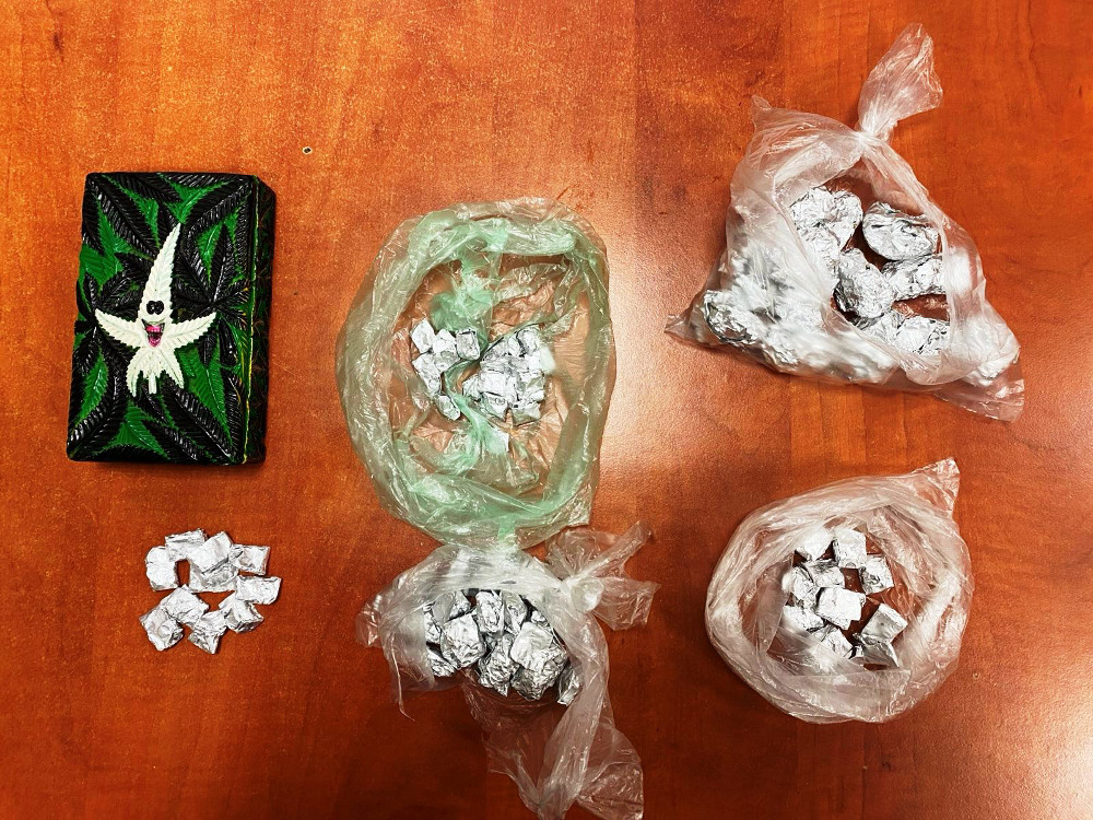 Na drewnianym blacie znajduje się kolorowe opakowanie z wizerunkiem postaci oraz cztery torebki foliowe z zawiniętymi w sreberko przedmiotami.