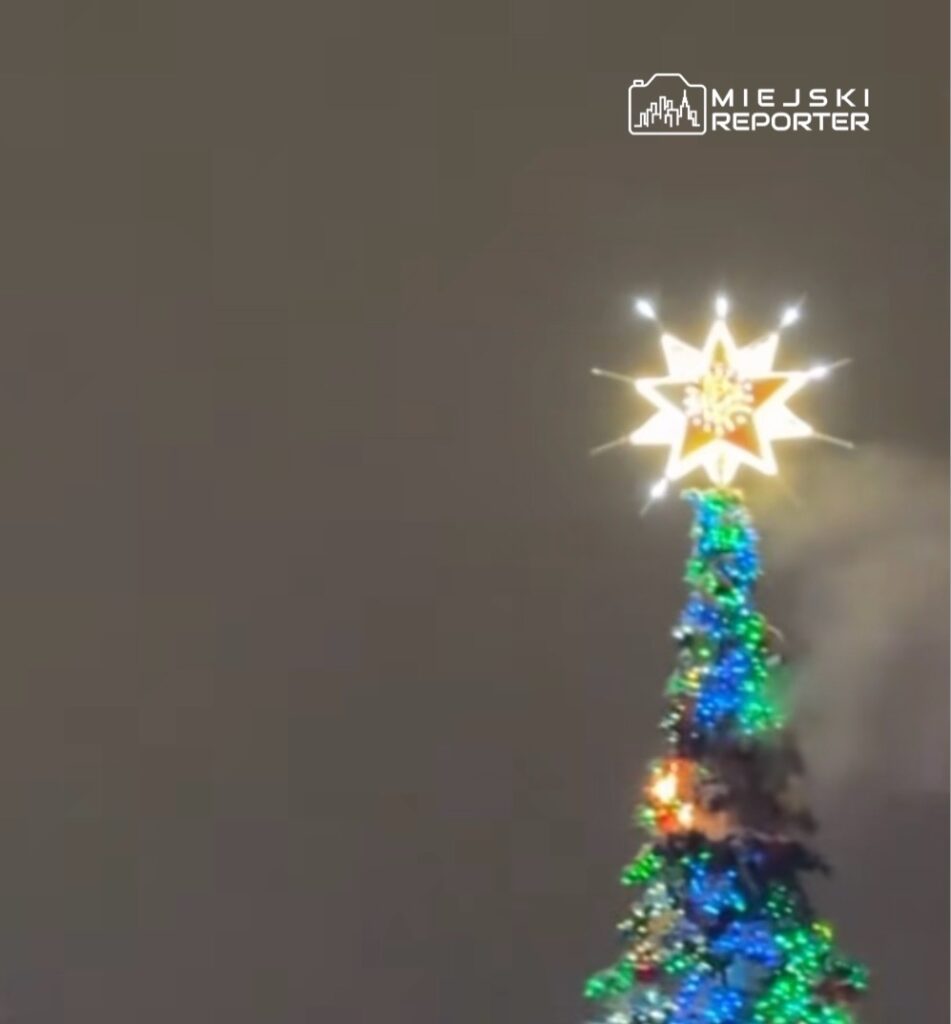 Świecąca gwiazda na szczycie kolorowo oświetlonej choinki, w tle szare niebo.