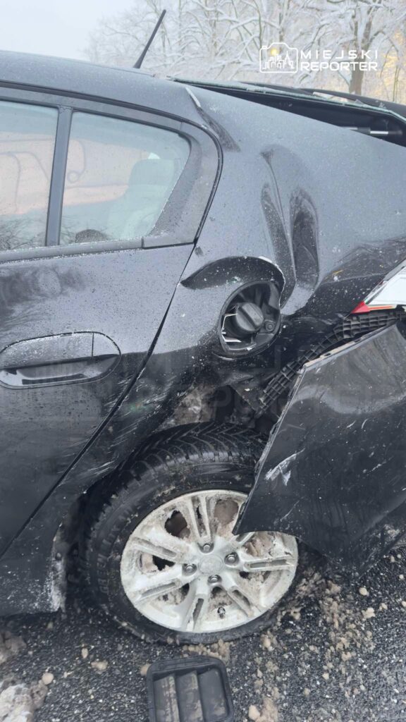 Czarny samochód osobowy z uszkodzeniami na tylnej karoserii stoi na zaśnieżonej drodze.