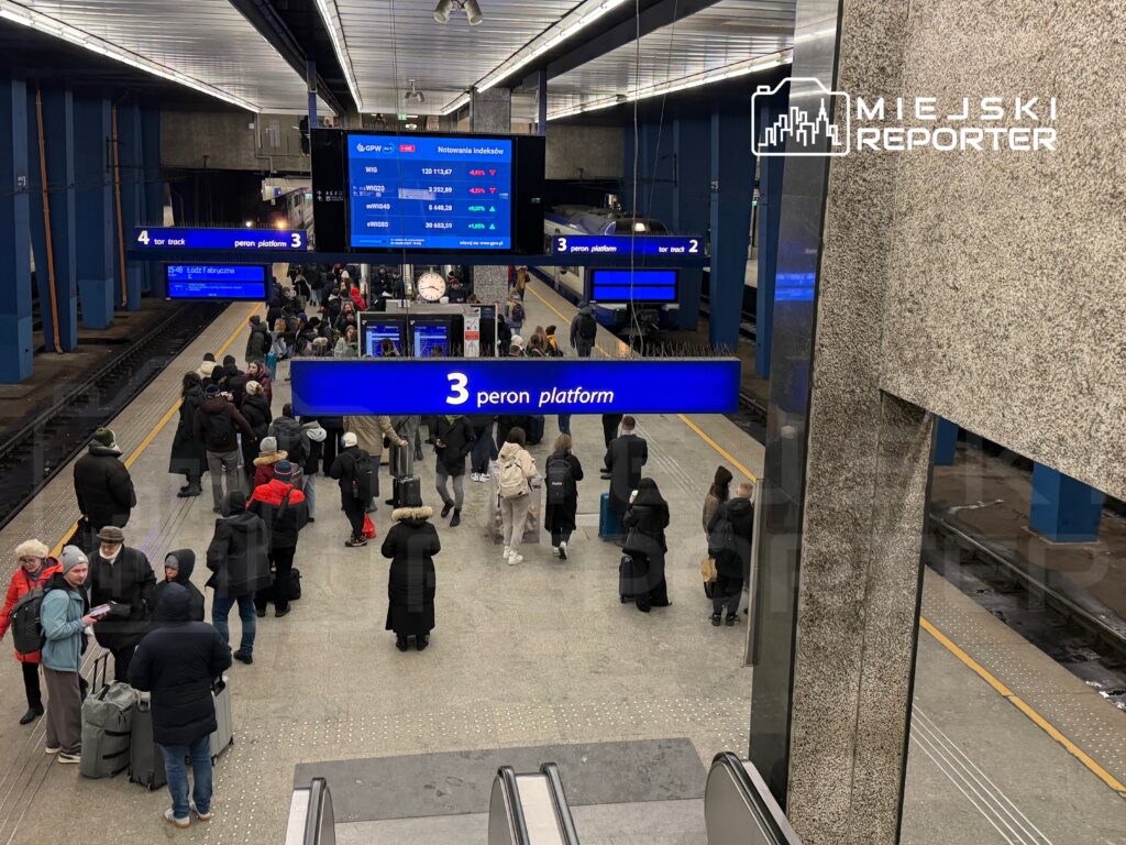 Tłum ludzi czeka na peronie 3 na stacji kolejowej, obok tablic z rozkładem jazdy i oznaczeniem torów.