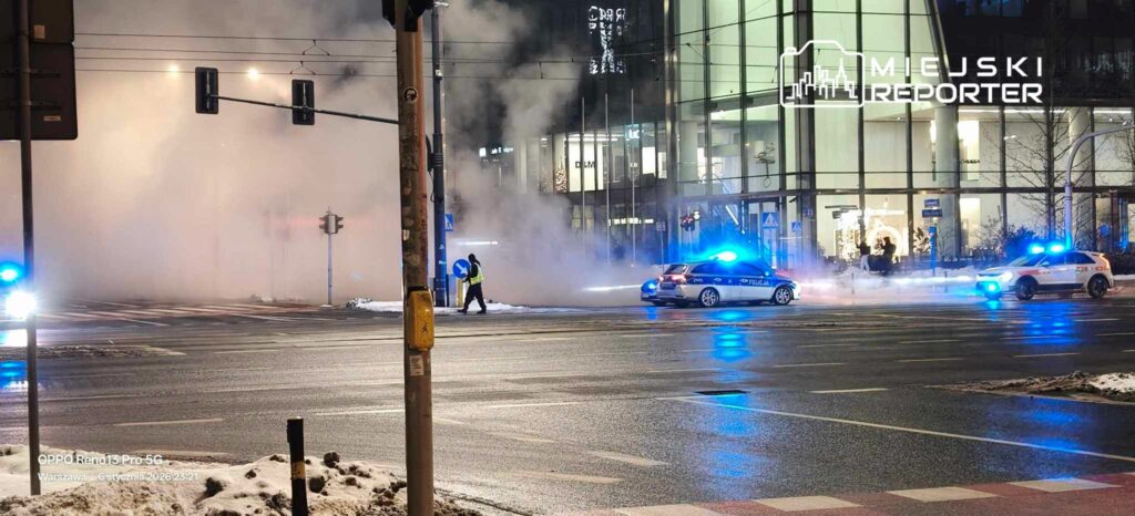 Policjanci w odblaskowych kamizelkach zabezpieczają miejsce zdarzenia w gęstej mgle, obok pojazdów służbowych.