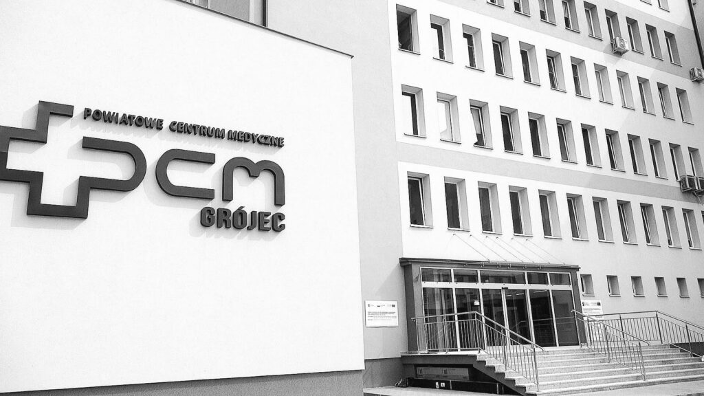 Nowoczesny budynek Powiatowego Centrum Medycznego z widocznym logo i schodami prowadzącymi do wejścia.