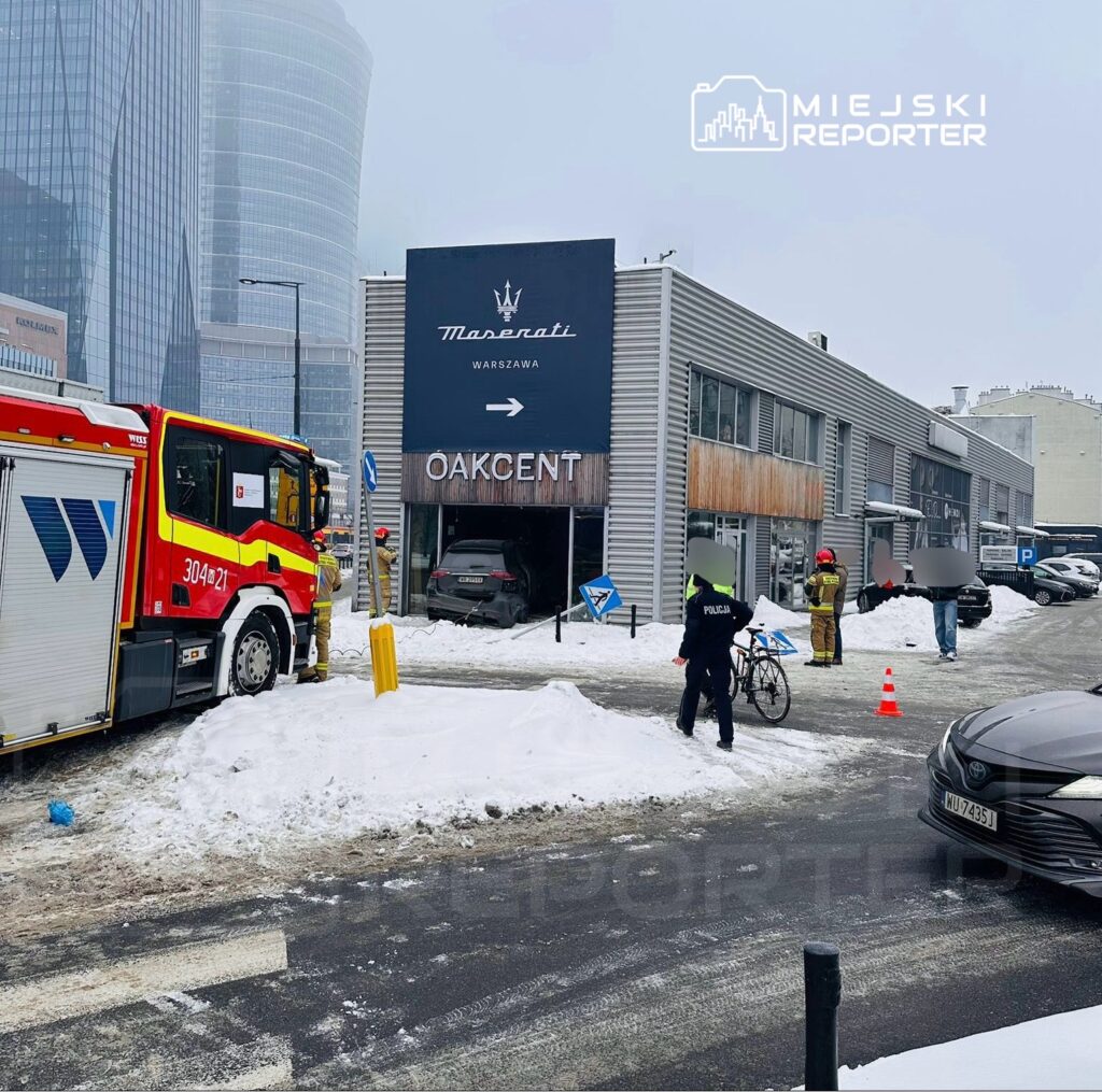 Strażacy i policjanci interweniują przy budynku Maserati w Warszawie, gdzie doszło do zdarzenia. W tle leży śnieg.