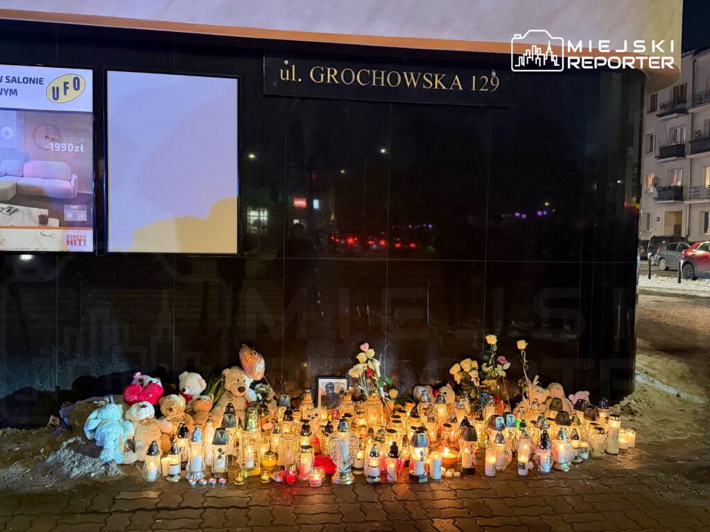 Świeczki i pluszowe misie ustawione w hołdzie przed czarną ścianą budynku przy ul. Grochowskiej 129.