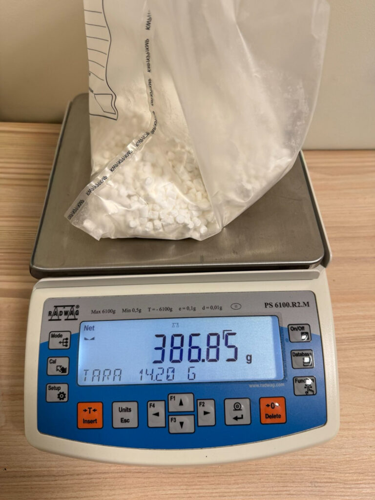 Biały proszek w przezroczystej torbie umieszczony na wadze elektronicznej, wskazującej 386.85 g.