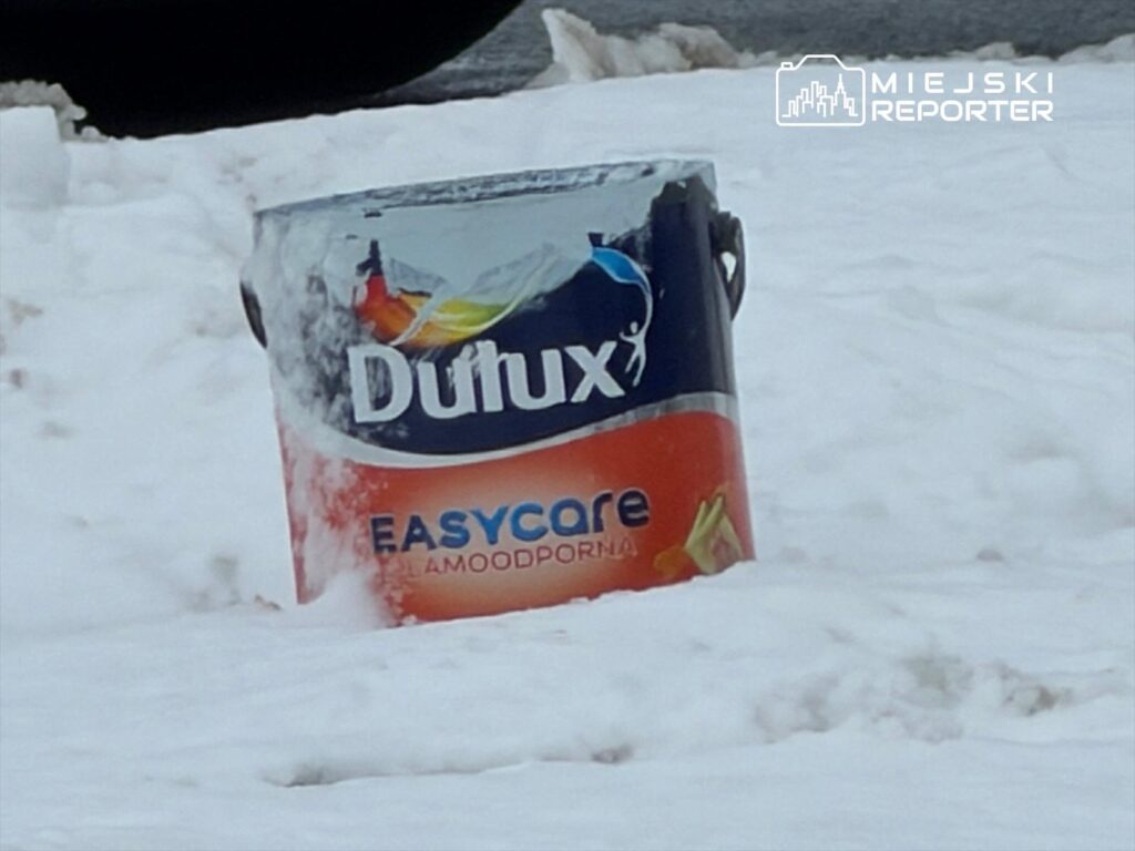 Pojemnik farby Dulux Easycare wystaje z zaspy śnieżnej na miejskiej ulicy.