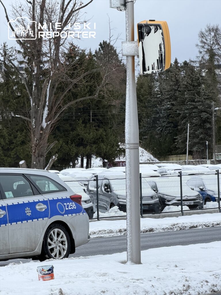 Policyjny radiowóz zaparkowany na zaśnieżonej ulicy obok zniszczonego sygnalizatora świetlnego.