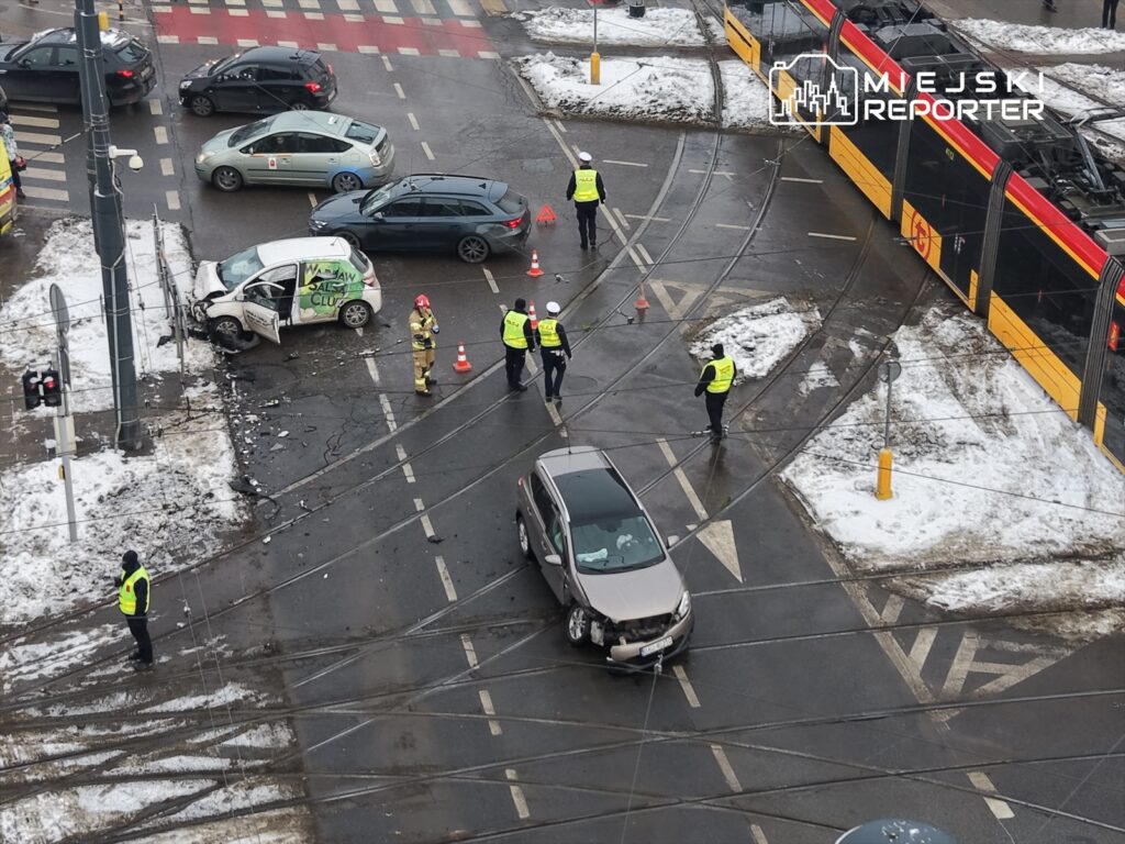 Wielu policjantów i strażaków zabezpiecza miejsce wypadku drogowego, gdzie zderzyły się dwa pojazdy.