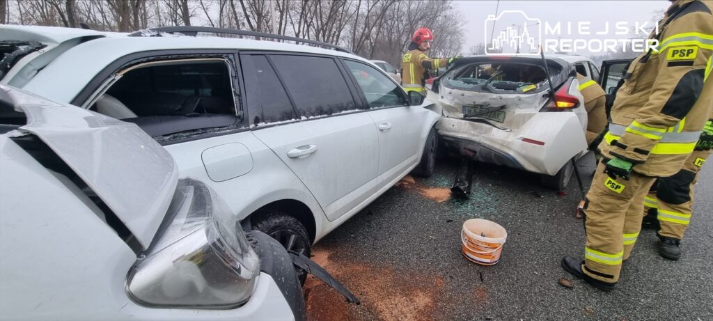 Wielka kolizja drogowa z udziałem dwóch uszkodzonych samochodów, w pobliżu pracujących strażaków.