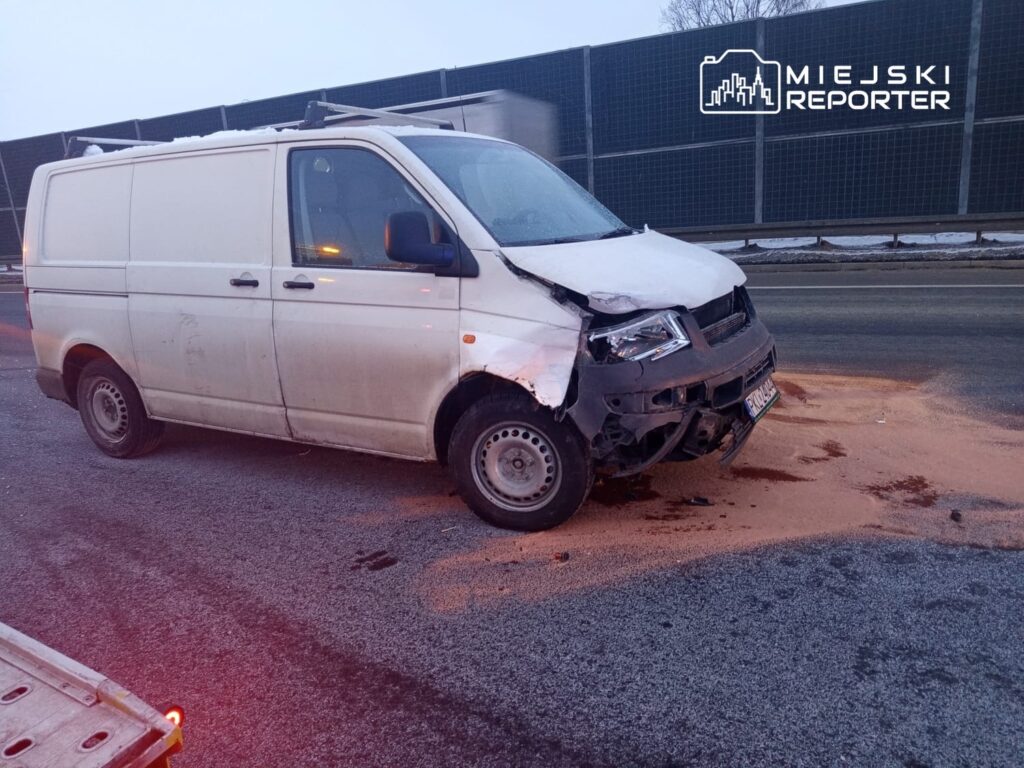 Uszkodzony biały furgon stoi na drodze, wokół niego rozlana substancja, prawdopodobnie olej.