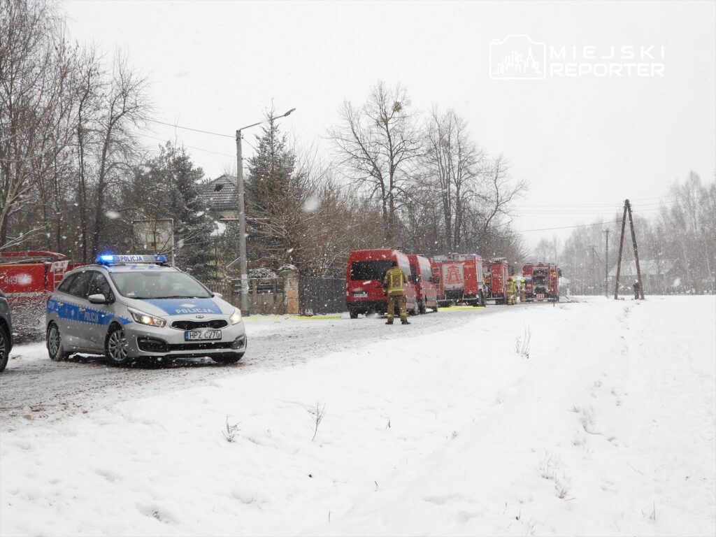 W trakcie zimowej burzy, policja i straż pożarna prowadzą działania ratunkowe na zaśnieżonej drodze.