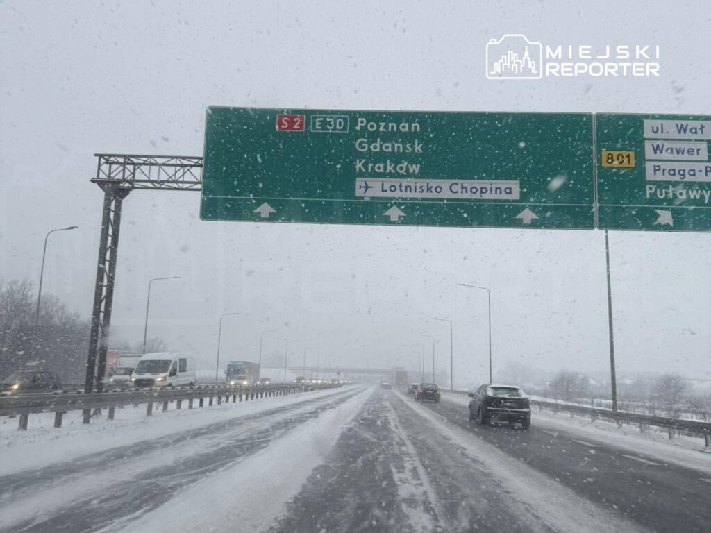 Droga ekspresowa w czasie intensywnej śnieżycy, widoczne znaki kierunkowe do Poznania, Gdańska i Krakowa.