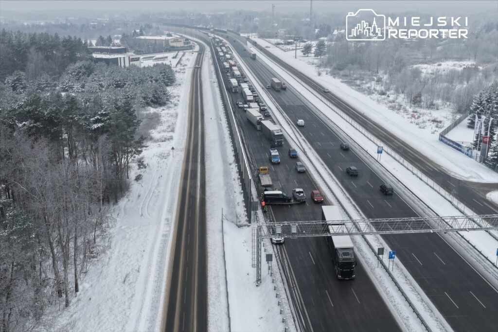 Ruch samochodowy na zamarzniętej autostradzie, w tle zalesione tereny pokryte śniegiem.
