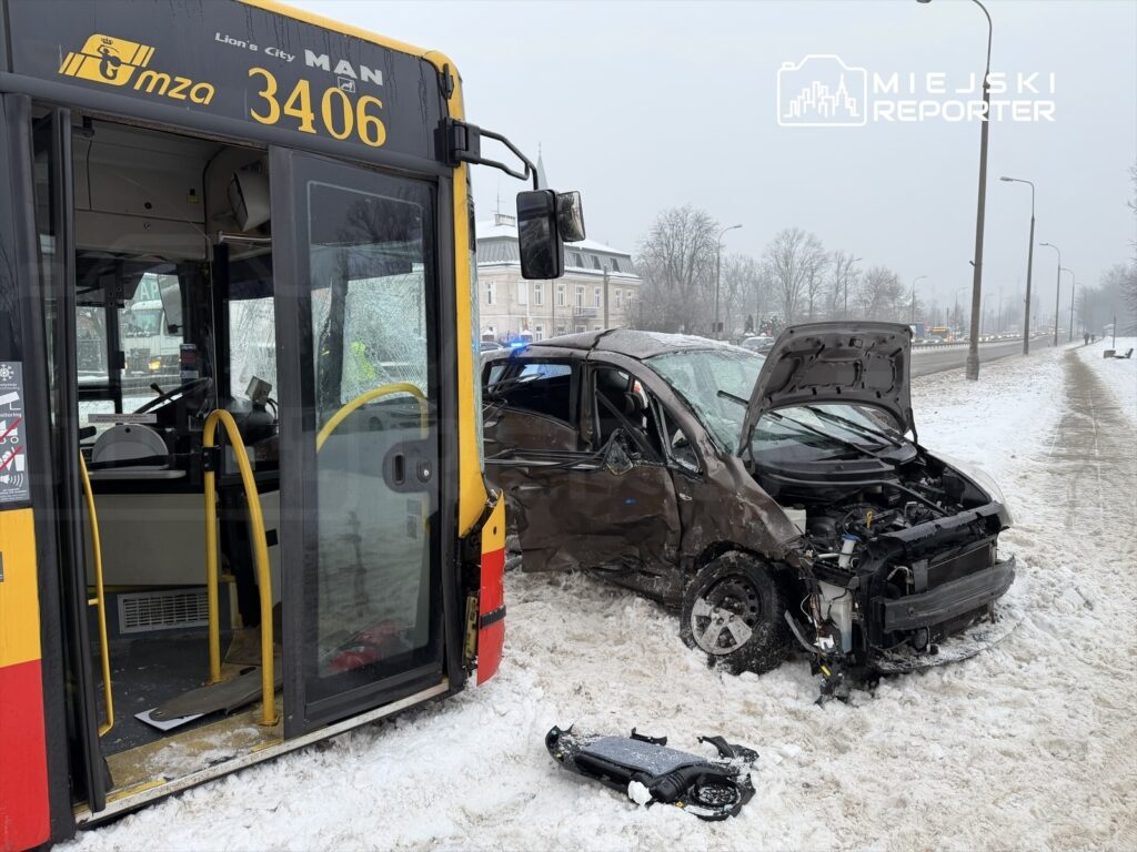 Zderzenie autobusu z osobowym samochodem w zaśnieżonym otoczeniu, z uszkodzeniami pojazdów i otwartą maską.