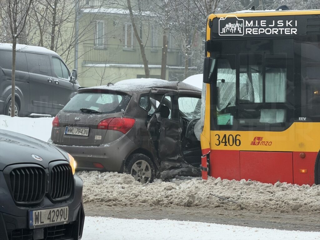 Zderzenie autobusu z osobowym samochodem na zaśnieżonej ulicy, z widocznymi uszkodzeniami pojazdów.