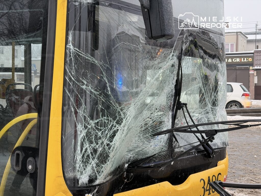 Zniszczona szyba przednia autobusu miejskiego z pęknięciami, stojącego na ulicy w zimowej scenerii.