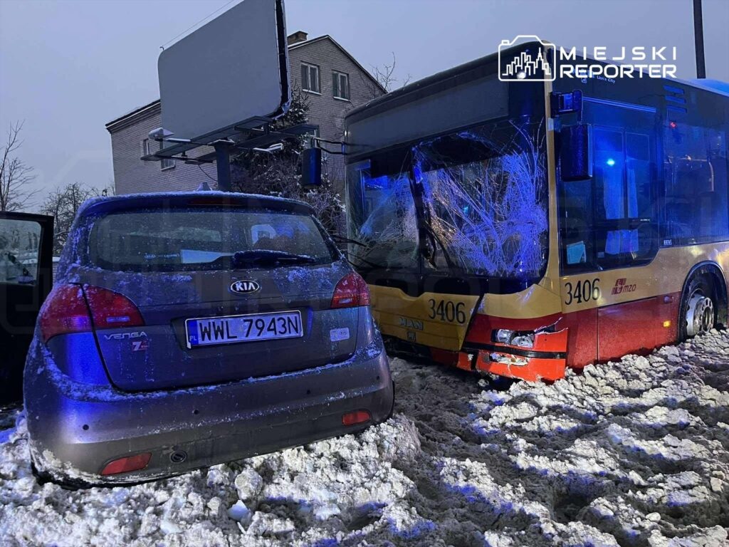 Zniszczony autobus z rozbitym przednim szkłem stoi obok zaparkowanego samochodu w śnieżnym otoczeniu.