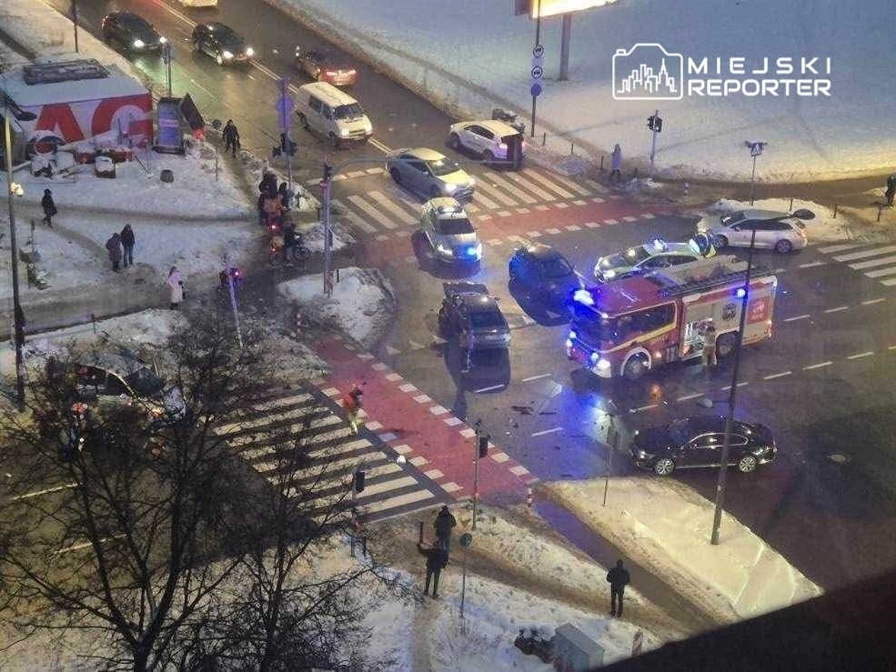 Wielu kierowców zatrzymanych w korku, obok samochodu strażackiego na skrzyżowaniu w zimowej scenerii.