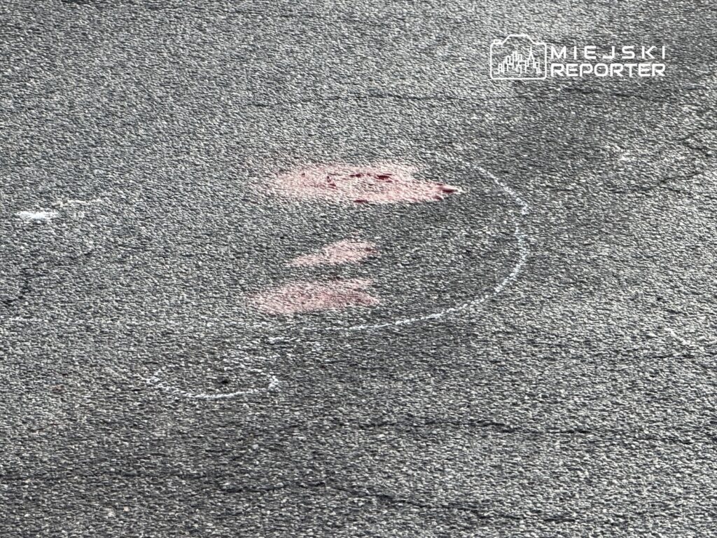 Na asfalcie widoczne są różowe i białe ślady w kształcie znaku zapytania.