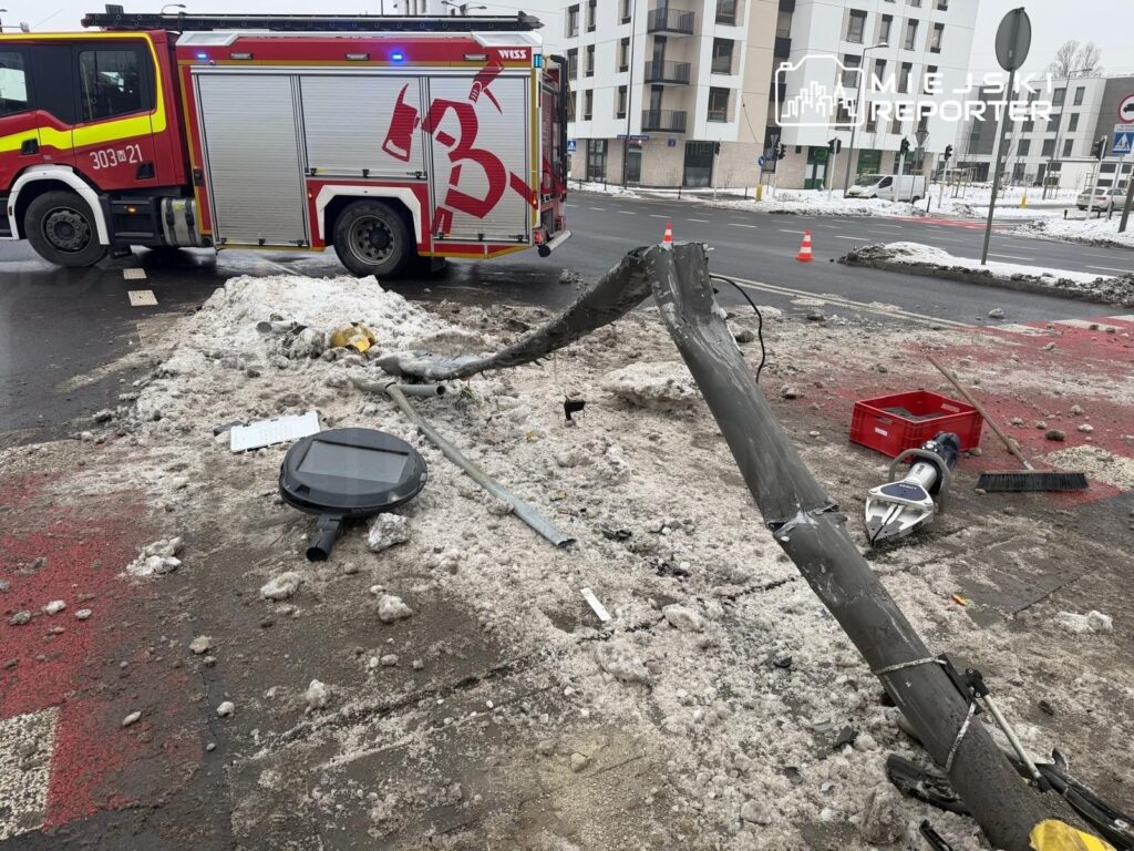 Straż pożarna zatrzymana obok uszkodzonego słupa energetycznego na zasypanej śniegiem ulicy.