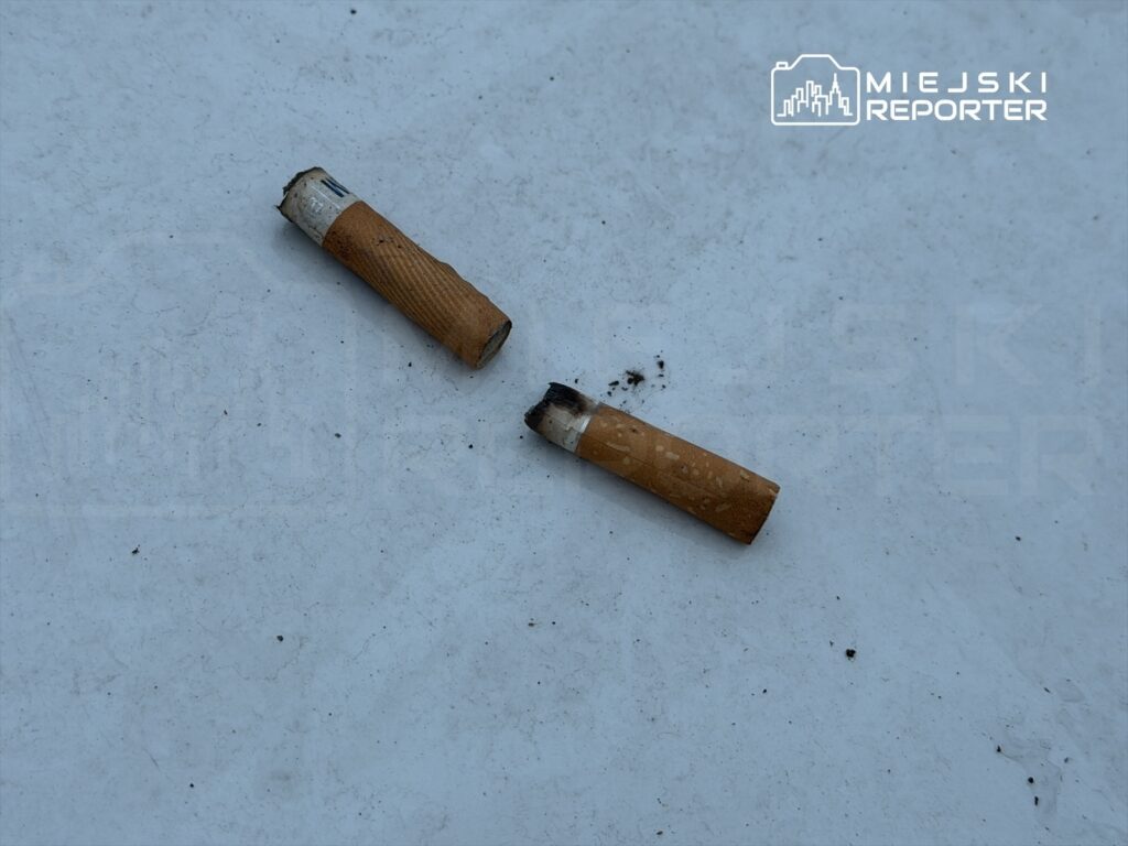 Na białej powierzchni leżą dwa niedopałki papierosów, jeden z nich lekko przypalony.