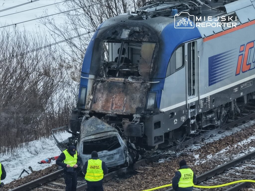 Pojazd kolejowy z uszkodzoną kabiną stoi na torach, obok pracują funkcjonariusze w żółtych kamizelkach.