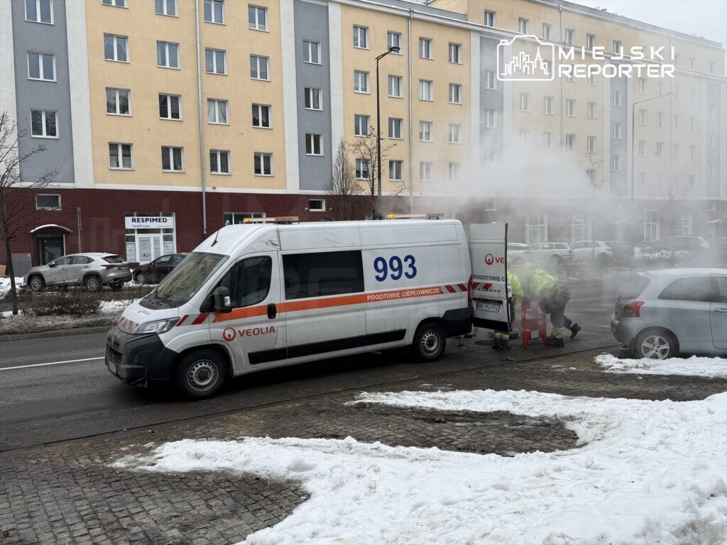 Zespół ratunkowy w żółtych kurtkach pracuje przy unieruchomionym pojeździe na zaśnieżonej ulicy.