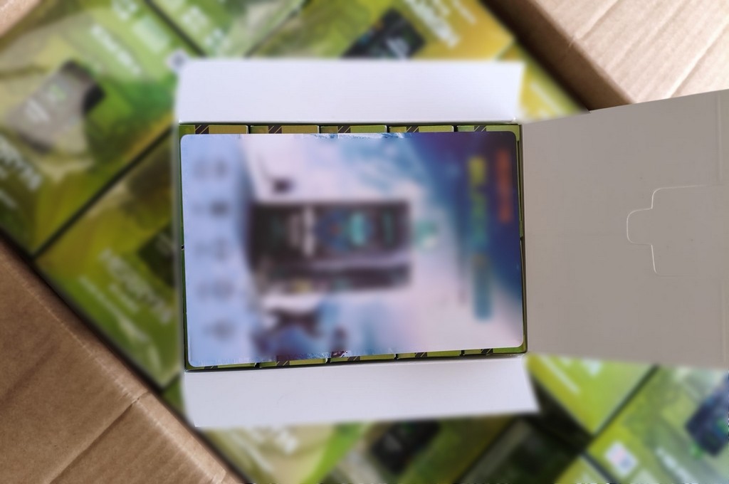 Otwarta teczka z grafiką na okładce, w tle widoczne pudełka z zielonymi etykietami.