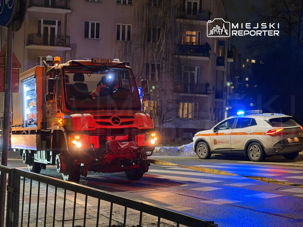 Czerwony samochód dostawczy z oświetleniem w nocy zatrzymany obok radiowozu policyjnego na ulicy w mieście.