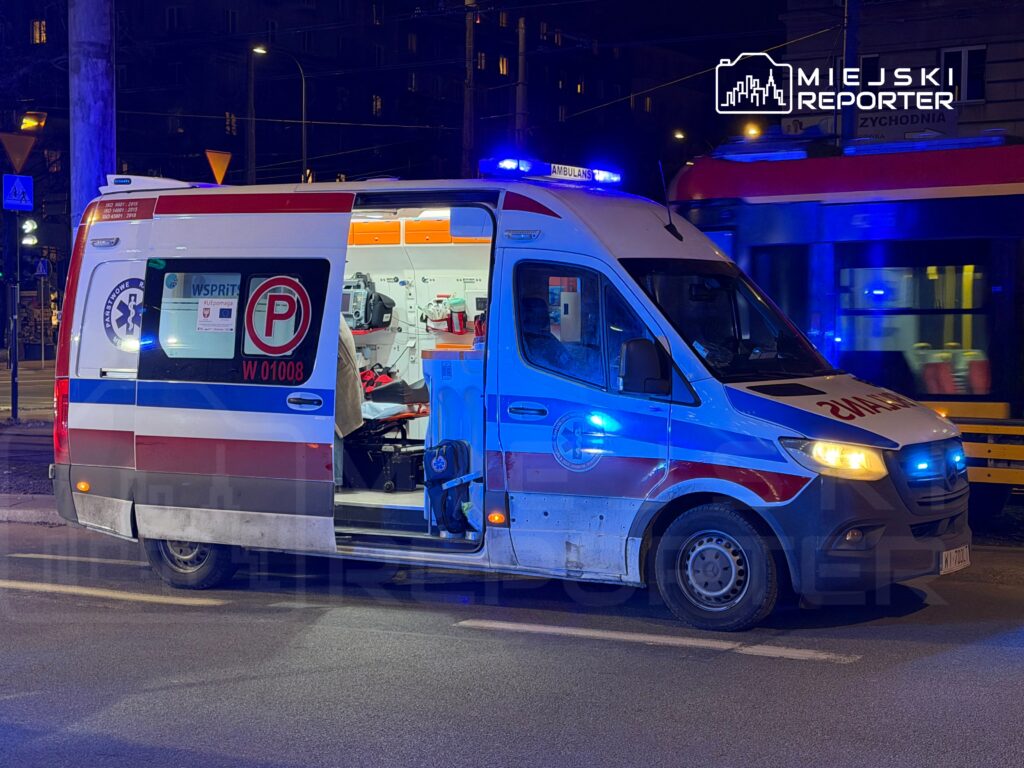 Karetka pogotowia z włączonymi sygnałami świetlnymi stoi na ulicy w nocy, widoczne wnętrze pojazdu.