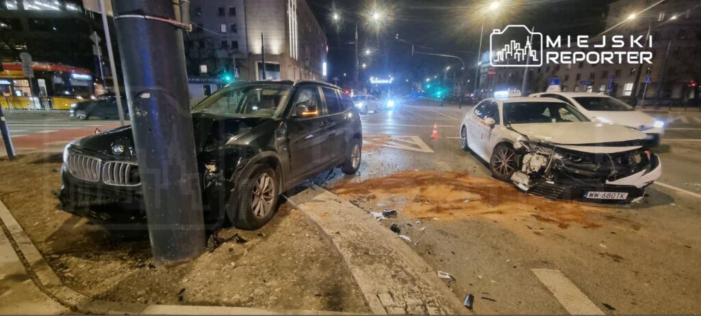 Dwa uszkodzone samochody osobowe stoją na skrzyżowaniu, jeden z nich uderzył w słup.