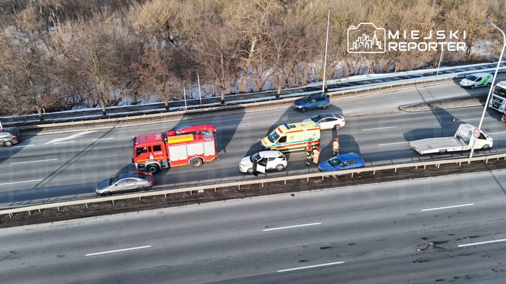 Wielu ratowników medycznych i strażaków udziela pomocy przy wypadku drogowym na ruchliwej jezdni.