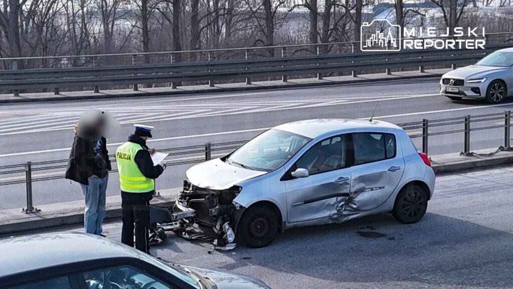 Policjant w kamizelce odblaskowej spisuje dane przy uszkodzonym samochodzie na ruchliwej ulicy.
