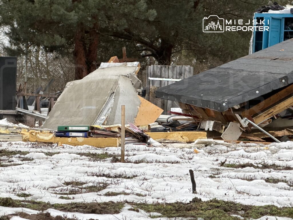 Zniszczona konstrukcja budowlana leży na śniegu, otoczona resztkami materiałów budowlanych.