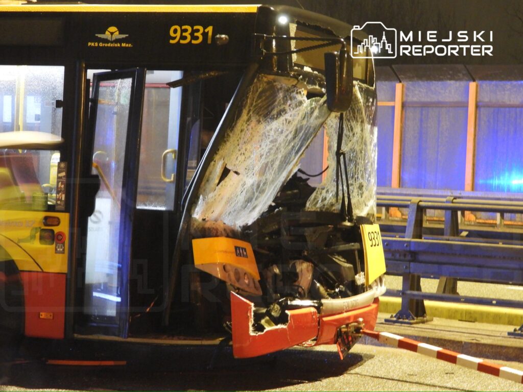 Uszkodzony autobus z rozbitą szybą i uszkodzoną przednią częścią stoi na jezdni, otoczony przez policyjny taśmę.