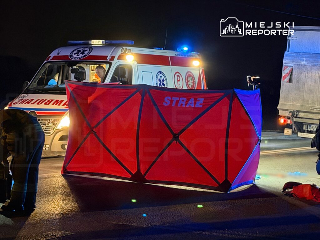 Zespół ratownictwa medycznego pracuje przy wypadku drogowym, obok czerwonego namiotu zabezpieczającego.