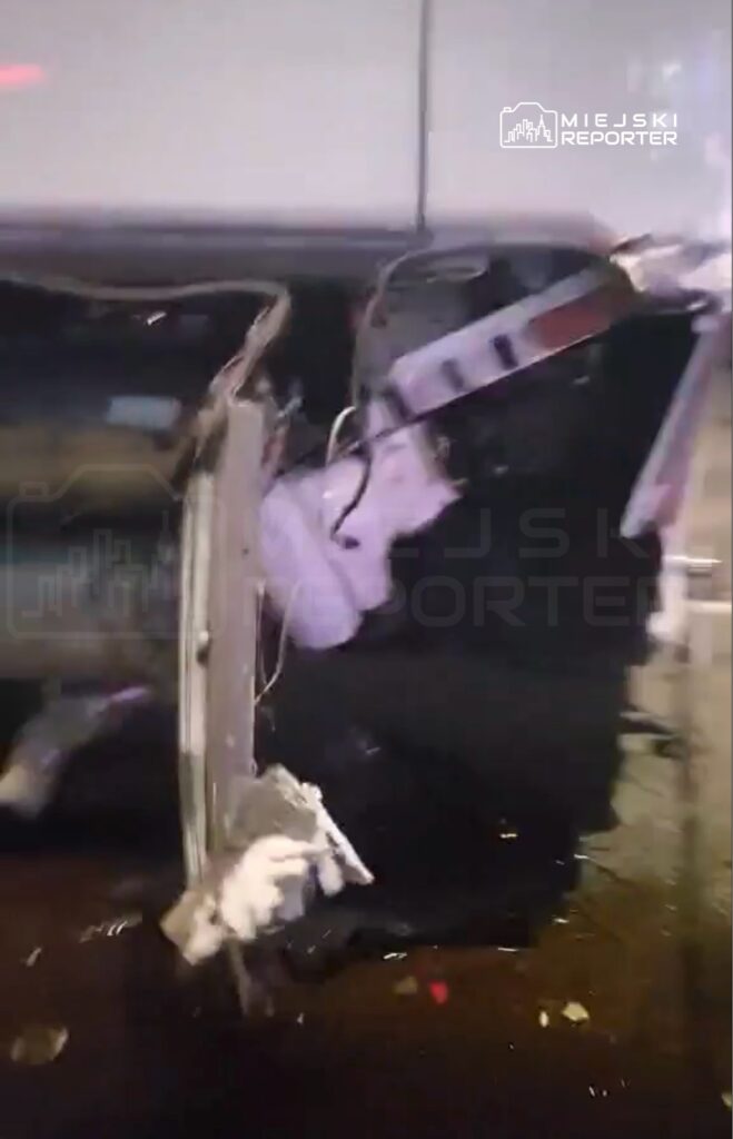 Uszkodzona karoseria pojazdu leżącego na boku, z widocznymi uszkodzeniami wnętrza oraz fragmentami elementów elektronicznych.
