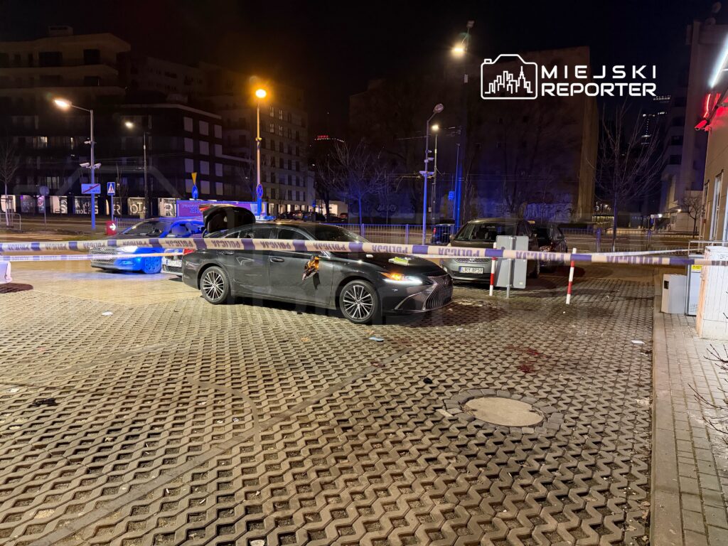 Samochód osobowy z uszkodzeniami stoi na oznakowanym terenie, otoczony taśmą policyjną w nocnej scenerii.