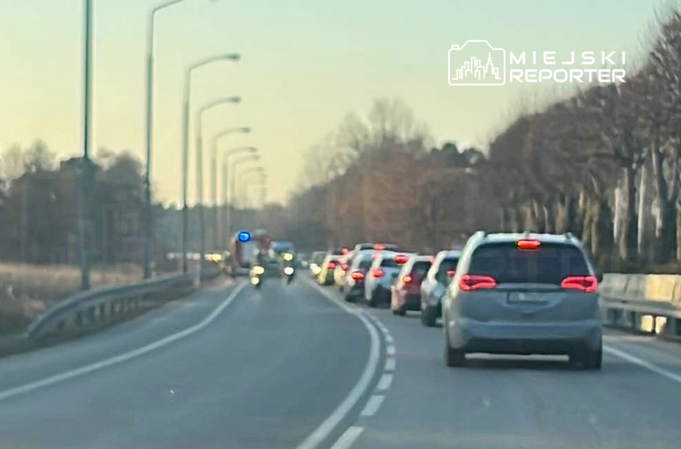 Karetka z włączonymi sygnałami świetlnymi przejeżdża obok zatoru drogowego na dwupasmowej drodze.