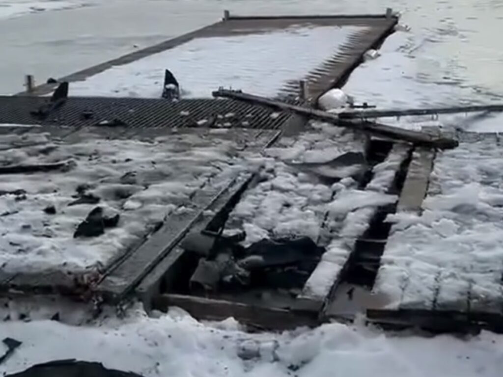 Zniszczony pomost pokryty śniegiem i lodem, z widocznymi uszkodzeniami w strukturze.