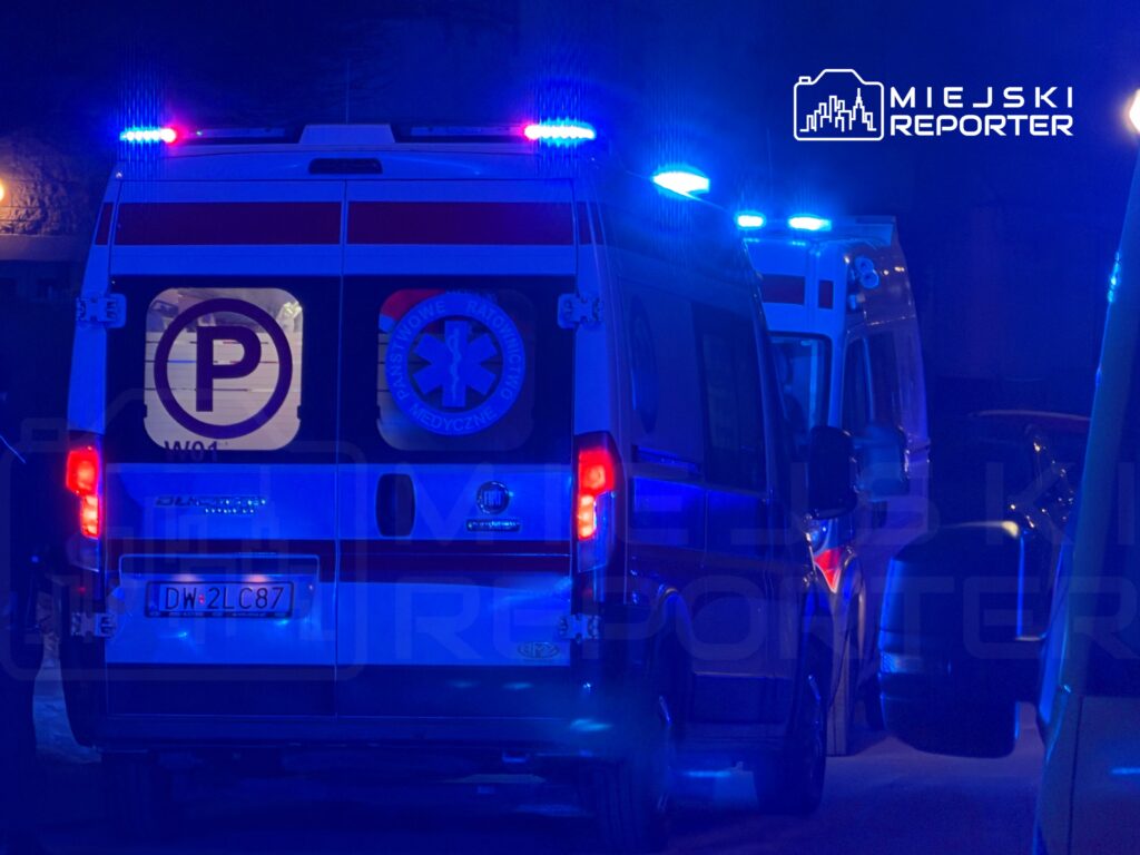 Karetka pogotowia z włączonymi sygnałami świetlnymi zatrzymana na ulicy w nocy.