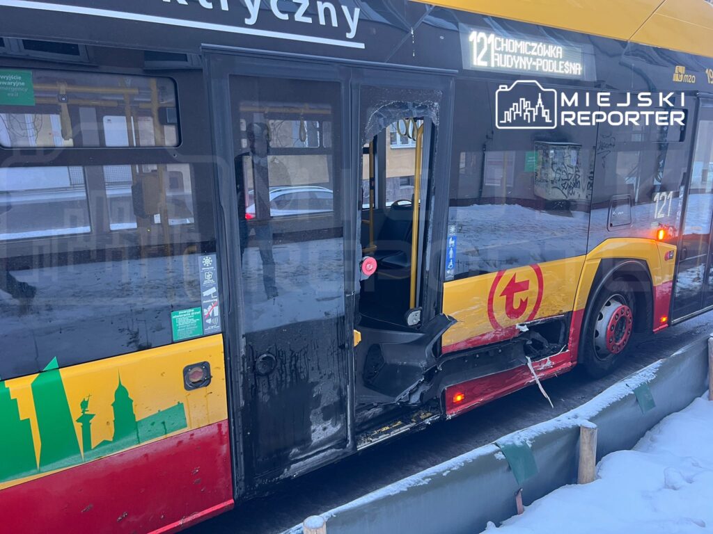 Autobus komunikacji miejskiej z uszkodzoną drzwiami stoi na zaśnieżonej ulicy, z widocznym numerem linii 121.