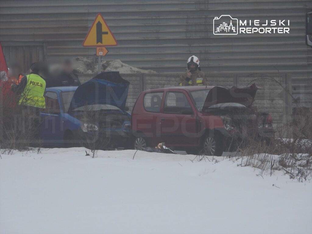 Policjant w kamizelce odblaskowej rozmawia z kierowcą przy dwóch uszkodzonych samochodach na zaśnieżonej drodze.