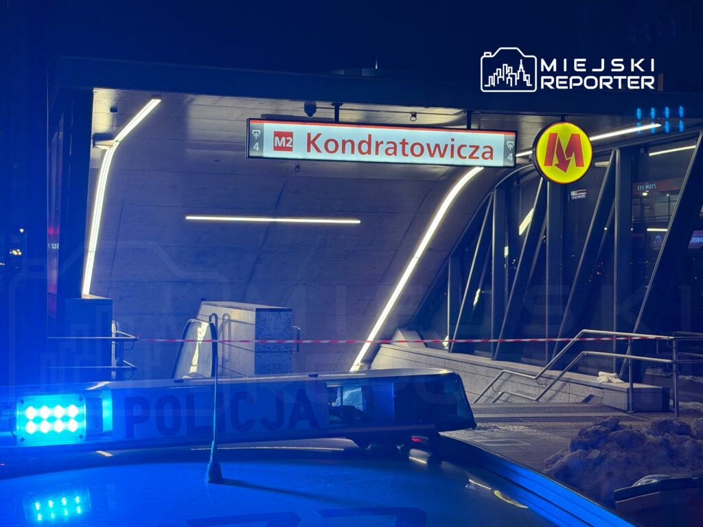 Stacja metra z oznaczeniem "Kondratowicza" oświetlona niebieskimi światłami policyjnymi i taśmą zabezpieczającą.